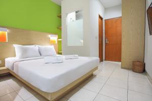 Un dormitorio con una gran cama blanca y una pared verde en LeGreen Suite Senayan, en Yakarta