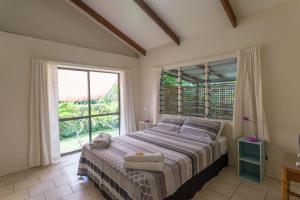 a bedroom with a bed and a large window at Mango Cottage in Rarotonga