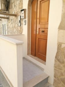 a hallway with a wooden door and a stone wall at Appartamento Tripoli in Vieste