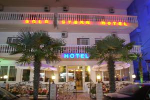 a hotel with two palm trees in front of it at Gold Stern in Paralia Katerinis