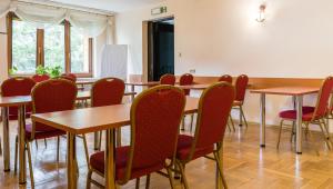 una sala da pranzo con tavoli in legno e sedie rosse di Hotel Boruta a Zakopane
