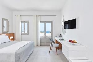 a bedroom with a bed and a desk and a television at Costa Grand Resort & Spa in Kamari +22 photos