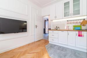 a kitchen with white cabinets and a flat screen tv at Old Town Heart V - Mariensztat in Warsaw