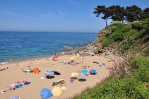a group of people on a beach with umbrellas at Le Braz Saint Lunaire in Saint-Lunaire
