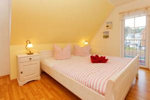 um quarto com uma cama branca com um arco vermelho em Ahornweg 7a em Ostseebad Karlshagen