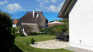 a house with a patio with an umbrella and chairs at Ahornweg 7a in Ostseebad Karlshagen