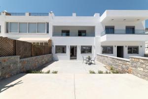 a white house with a stone wall at Aegean Treasure Pefkos in Pefki