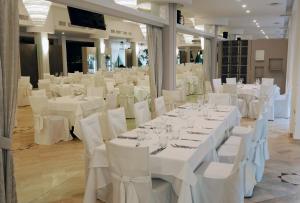 a banquet hall with white tables and white chairs at Hotel Molino Rosso in Imola