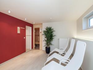 Habitación con sillas blancas y pared roja. en Ferienwohnung Strandkörbchen, en Juliusruh