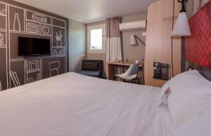 a bedroom with a large white bed and a desk at IBIS Lyon Sud Chasse Sur Rhône in Chasse-sur-Rhône