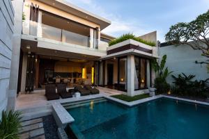 a house with a swimming pool in front of a house at Villa Portsea in Seminyak