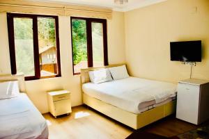 a bedroom with two beds and a tv and windows at Isikli Kale Hotel in Çaykara
