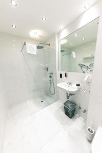 ein weißes Bad mit einer Dusche und einem Waschbecken in der Unterkunft Altstadthotel Kasererbräu in Salzburg