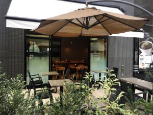 a patio with tables and chairs and an umbrella at APA Hotel Shin Osaka Ekiminami in Osaka