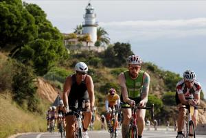 a group of people riding bikes down a road with a lighthouse at CALELLA DE LA COSTA ( Maresme - Costa Brava) in Calella