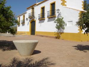 un edificio blanco y amarillo con una olla delante de él en Cortijo Molino San Juan en Montoro