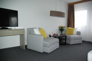 a living room filled with furniture and a tv at astral'Inn Leipzig Hotel & Restaurant in Leipzig