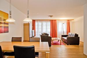 een woonkamer met een tafel en stoelen en een bank bij Apartment Stotzhalten 2.5 - GriwaRent AG in Grindelwald