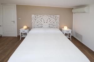 villa aurora في جيارديني ناكسوس: غرفة نوم بسرير ابيض كبير مع طاولتين