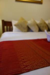 a close up of a bed with red sheets and pillows at Smile Society in Bangkok