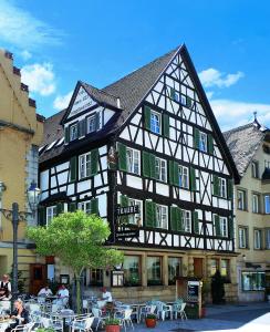 ein großes schwarzweißes Gebäude mit Tischen und Stühlen in der Unterkunft Hotel Traube in Sigmaringen