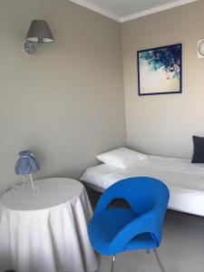 ジェロナ・グラにあるSANTOSA Pokoje Goscinneのベッド2台、テーブルの横に青い椅子が備わる客室です。