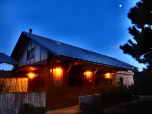 una casa in legno con luci accese di notte di Waterside Cottage Heron a Kyotango