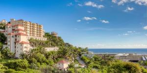 a building on a hill next to the ocean at Princess Heights Luxury Condo Hotel in Dawn Beach