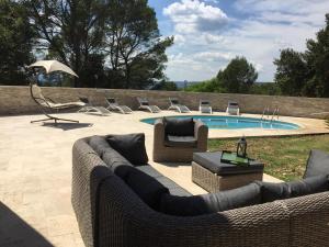 a patio with a couch and chairs and a pool at Villa « CHANTERIE » in Villecroze
