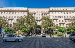 een witte auto geparkeerd voor een groot gebouw bij Check Inn Tbilisi in Tbilisi City