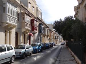 a row of parked cars on a city street at Granny's Inn Hostel in Sliema