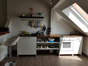 una cocina en el ático con armarios blancos y una ventana en Ferienwohnung an der Unditz, en Neuried