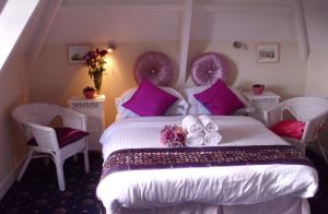 a bedroom with a large white bed with purple pillows at Estoril in Penzance