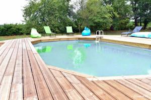 una gran piscina con terraza de madera y suelo de madera en Au petit prince de Lue en Lue
