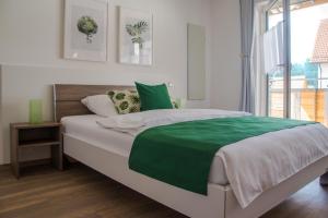 ein Schlafzimmer mit einem großen Bett und einer grünen Decke in der Unterkunft Moserhof-Apartments in Igersheim