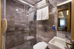 y baño con ducha, aseo y lavamanos. en Meretto Hotel LALELİ en Estambul