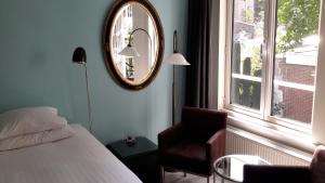a bedroom with a bed and a mirror and a chair at Bed & Breakfast WestViolet in Amsterdam