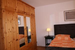 Schlafzimmer mit einem Bett und einem Holzschrank in der Unterkunft Nickelshus Whg. Robin in Sankt Peter-Ording