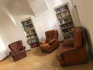 un soggiorno con 3 sedie e librerie di Albergo e Ostello della gioventù Biella centro storico a Biella