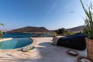 a swimming pool with a bed next to the water at Panormos Village Hotel in Mykonos