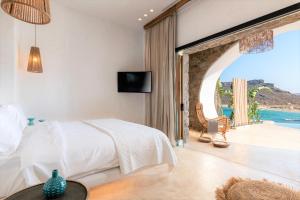 a bedroom with a bed and a view of the ocean at Panormos Village Hotel in Panormos Mykonos +163 photos