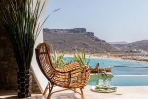 a rattan chair sitting on a patio with a view of a beach at Panormos Village Hotel in Mykonos