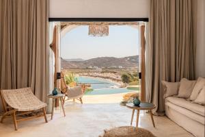 a living room with a couch and a view of the ocean at Panormos Village Hotel in Mykonos