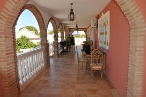 un pasillo de una casa con arcos, mesas y sillas en Chambres chez l'habitant Alhaurin, en Alhaurín de la Torre