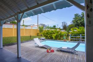 a pool with two chairs and a table next to it at Villa Bel Plaisi in Le Moule