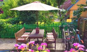 a table and chairs with an umbrella and some flowers at Vaivorykštė in Nida