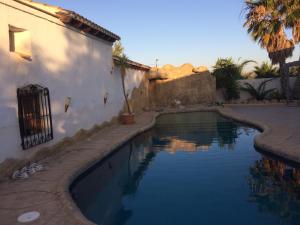 a swimming pool next to a white building with palm trees at Casa Pasy in Casas del Aljibe