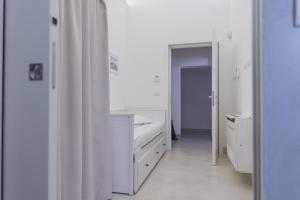 biały pokój z łóżkiem i lustrem w obiekcie CASA MELIO' w mieście Polignano a Mare