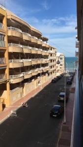 una calle con coches estacionados frente a un edificio en Apartamento playa Guardamar del Segura, en Guardamar del Segura