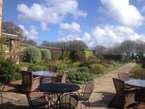 un patio avec des tables et des chaises dans un jardin dans l'établissement Greywalls Hotel & Chez Roux, à Gullane